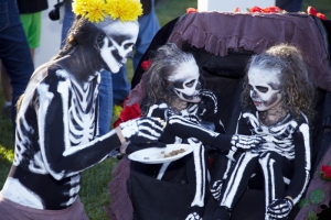 Mother dressed like a skeleton offers food to her twin girls also dressed like skeletons at  Day of the Dead (Dia de los Muertos) at Hollywood Forever cemetery