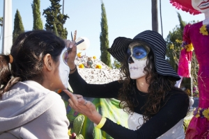 Woman paints girls face at Day of the Dead (Dia de los Muertos) at Hollywood Forever cemetery